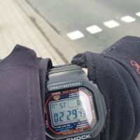 A digital wristwatch being used as a stopwatch with a street in the background