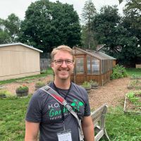 Sean Ferguson standing in front of a middle school garden installed and run by the non-profit H.O.P.E. Gardens Grand Rapids