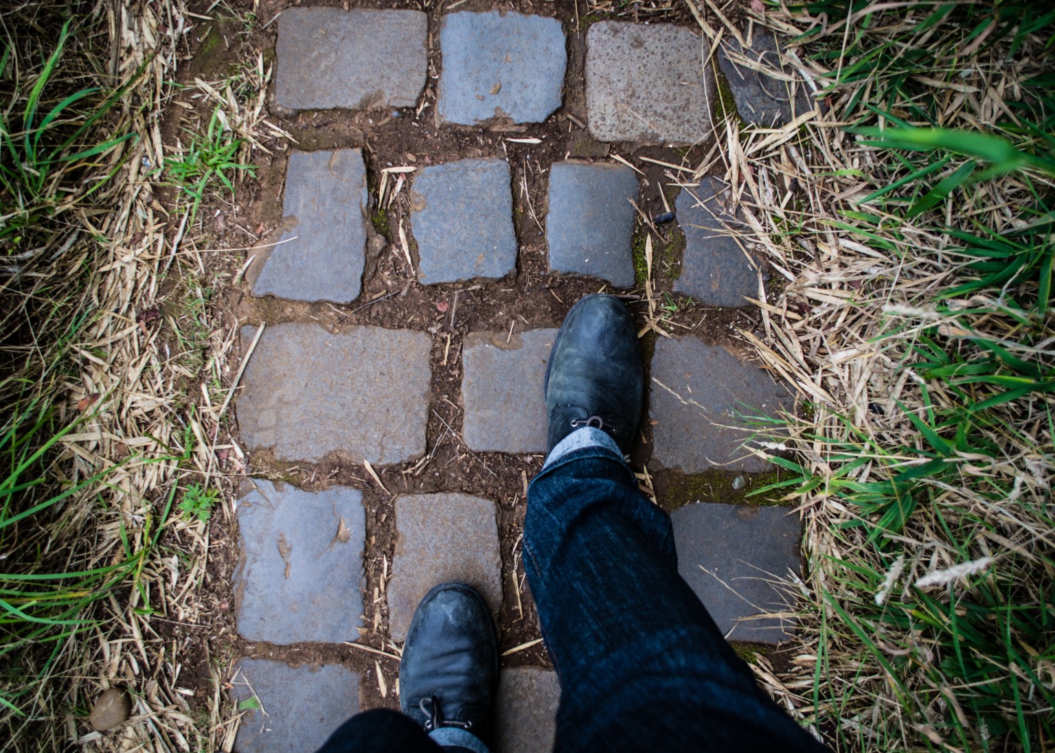 shot of feet of person walking on a cobbled pathway in what looks like a garden or nature path