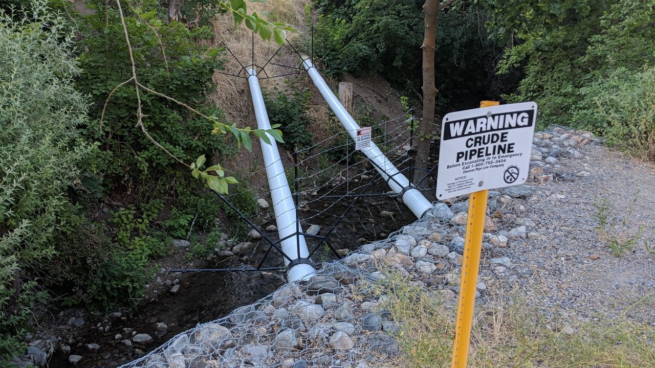 Crude oil pipe running exposed over a creek leading into downtown Salt Lake City, Utah, US